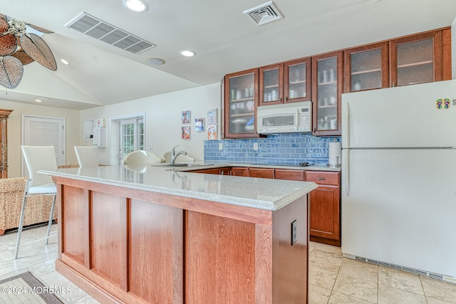 kitchen featuring vaulted ceiling, tasteful backsplash, white appliances, light tile patterned floors, and sink