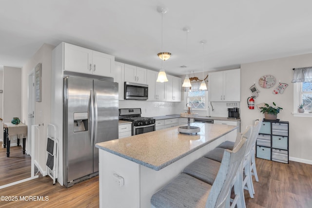 318 Bayview Ave, Union Beach, NJ 07735 - kitchen with appliances with stainless steel finishes, dark wood-type flooring, a center island, light stone countertops, and white cabinetry
