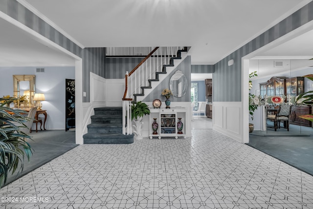 carpeted foyer featuring crown molding