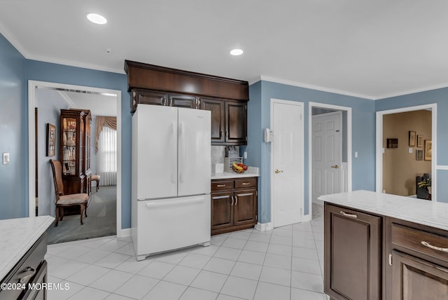 kitchen with dark brown cabinetry, crown molding, light tile patterned floors, and white refrigerator