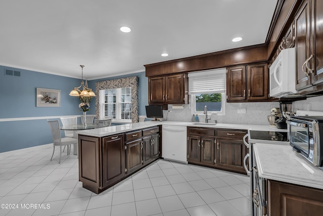 kitchen with sink, a notable chandelier, kitchen peninsula, white appliances, and decorative light fixtures