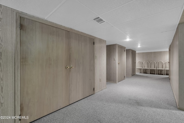 corridor featuring wood walls and light colored carpet