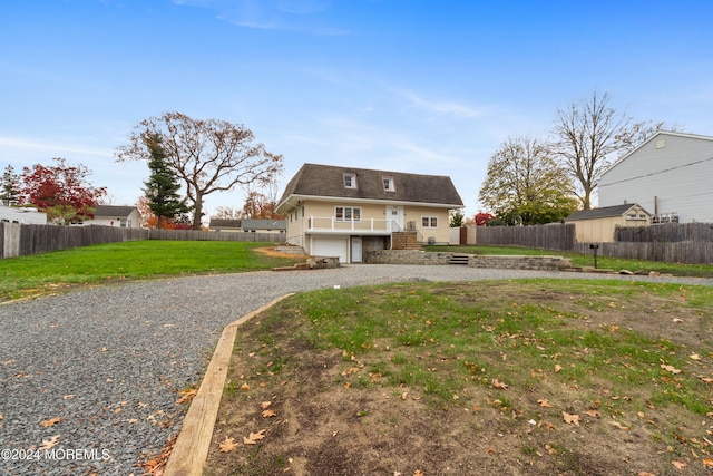 back of property with gravel driveway, a lawn, stairway, a garage, and a fenced backyard