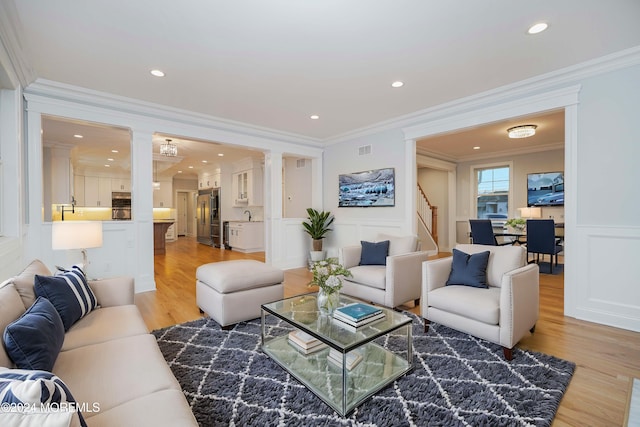 living room with light hardwood / wood-style flooring, crown molding, and sink