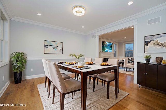 dining room with crown molding and light hardwood / wood-style flooring