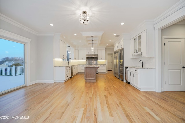 kitchen featuring white cabinetry, a center island, sink, light stone counters, and light hardwood / wood-style flooring