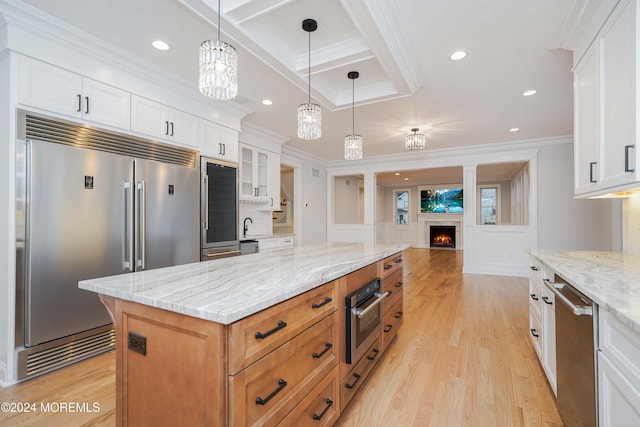 kitchen with light stone counters, a center island, white cabinets, and appliances with stainless steel finishes