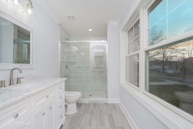 bathroom with vanity, toilet, ornamental molding, and walk in shower