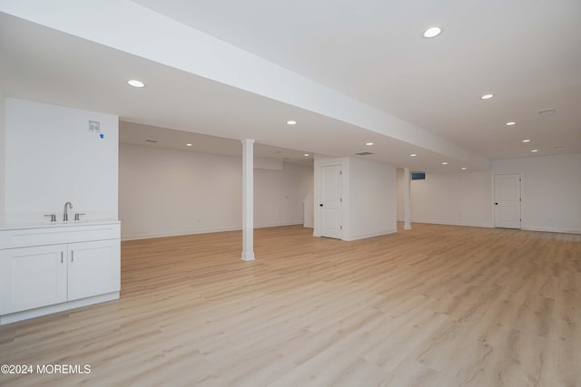 basement featuring light hardwood / wood-style floors and sink