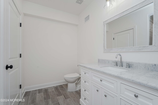 bathroom with toilet, vanity, and hardwood / wood-style flooring