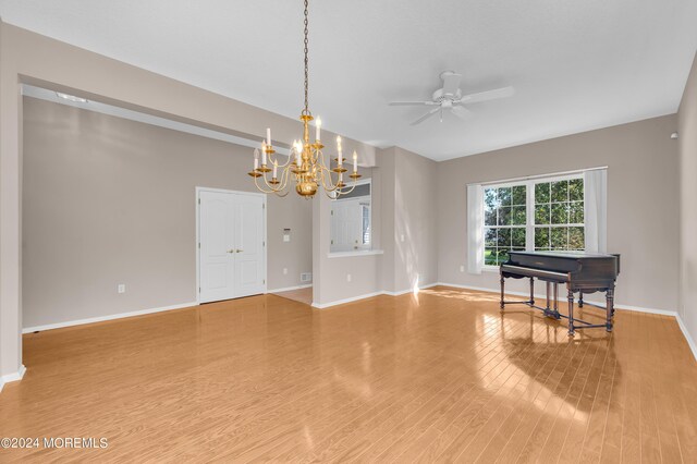 spare room featuring ceiling fan with notable chandelier and hardwood / wood-style flooring