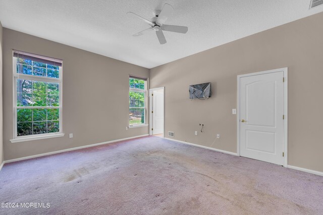 carpeted spare room featuring ceiling fan and a textured ceiling