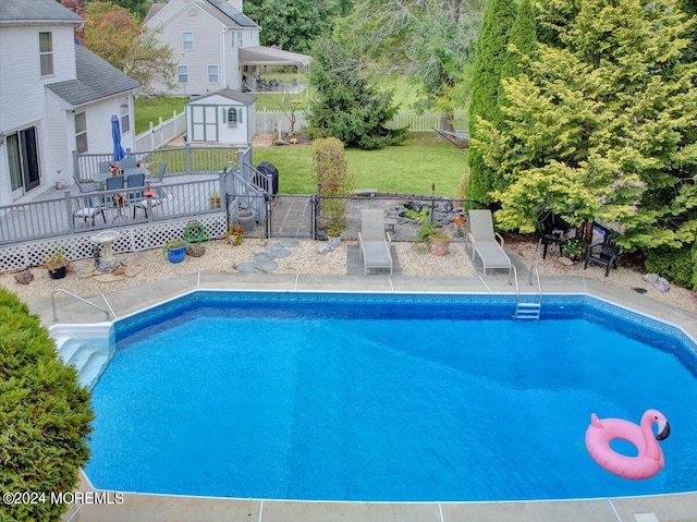 view of pool with a wooden deck, a yard, and a storage unit