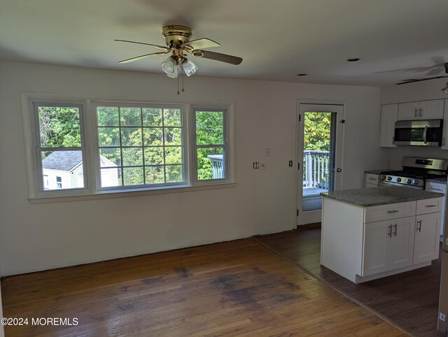 kitchen with appliances with stainless steel finishes, dark hardwood / wood-style flooring, ceiling fan, stone counters, and white cabinets