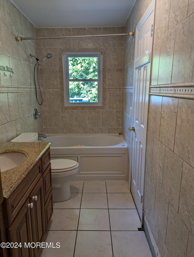 full bathroom featuring tiled shower / bath, vanity, toilet, and tile walls