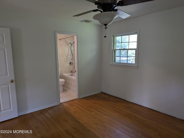 unfurnished bedroom with ceiling fan, light hardwood / wood-style floors, and connected bathroom