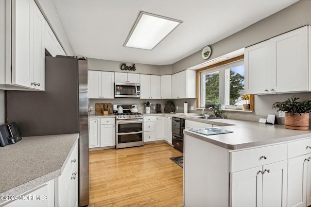 kitchen with light hardwood / wood-style floors, white cabinets, stainless steel appliances, and sink