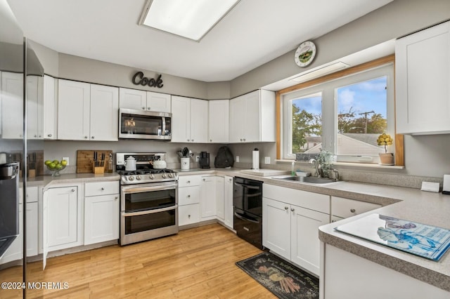 kitchen with appliances with stainless steel finishes, light hardwood / wood-style flooring, white cabinets, and sink