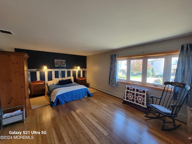 bedroom with wood-type flooring and a baseboard heating unit