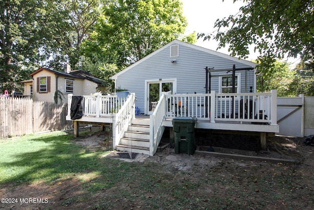 back of property with a yard and a wooden deck