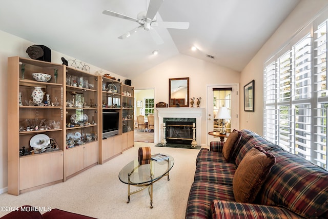 carpeted living room with a premium fireplace, ceiling fan, and vaulted ceiling