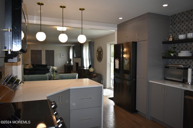 kitchen with pendant lighting, hardwood / wood-style flooring, black fridge, kitchen peninsula, and gray cabinetry