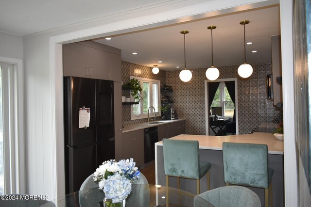 kitchen featuring kitchen peninsula, decorative backsplash, a kitchen breakfast bar, black appliances, and decorative light fixtures