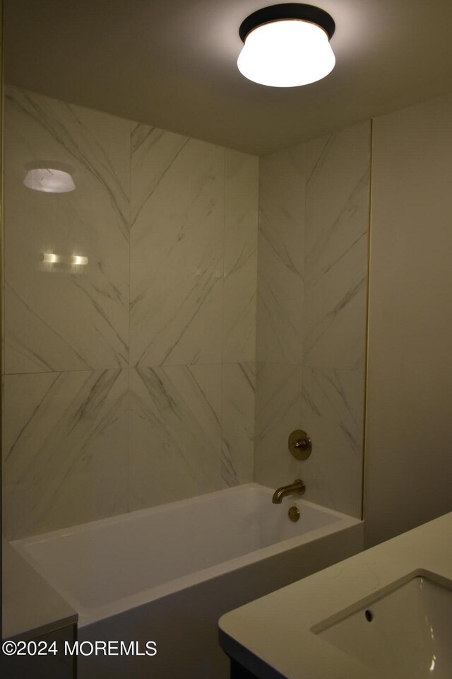 bathroom with tiled shower / bath and vanity