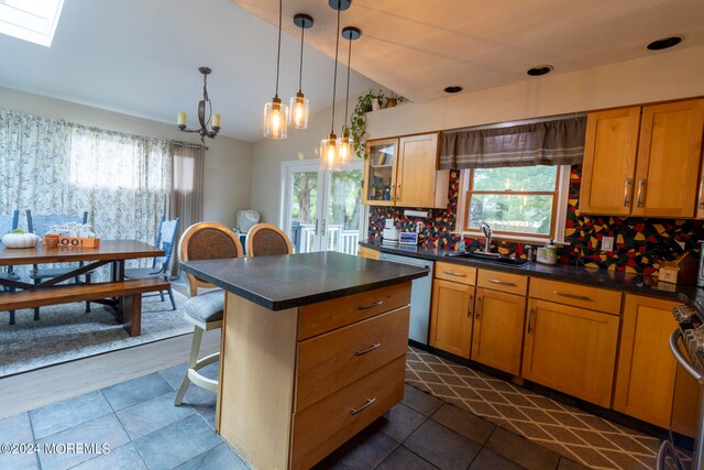 kitchen with sink, tasteful backsplash, decorative light fixtures, lofted ceiling with skylight, and a breakfast bar area