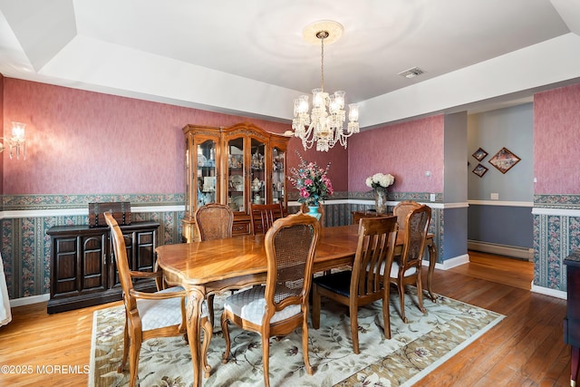 dining area featuring a baseboard radiator, light wood finished floors, baseboards, and wallpapered walls