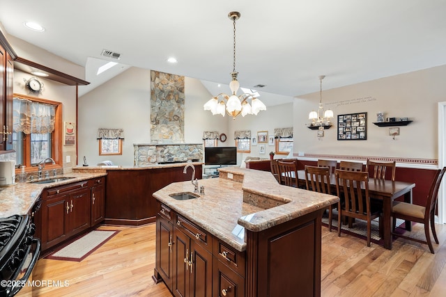 kitchen featuring black gas range, light wood-style flooring, a sink, and visible vents