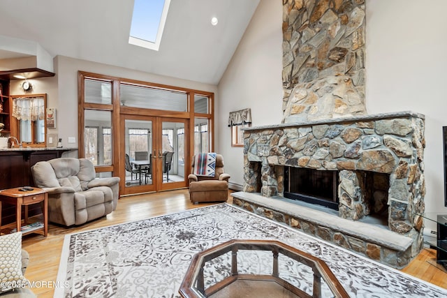 living room with a fireplace, high vaulted ceiling, wood finished floors, and french doors