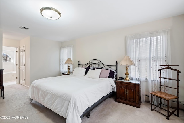 bedroom featuring ensuite bath, visible vents, and light colored carpet