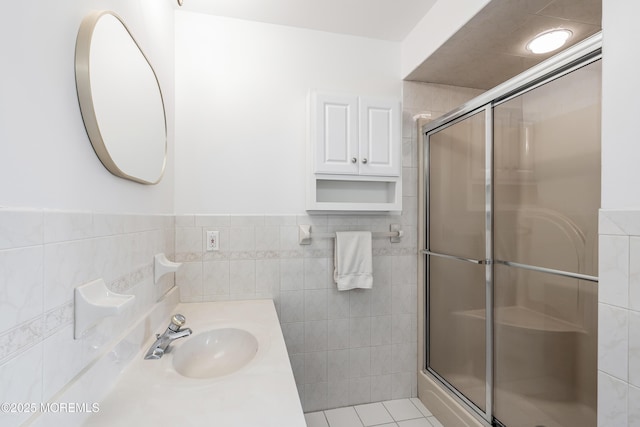 bathroom featuring vanity, a shower stall, tile walls, and tile patterned floors