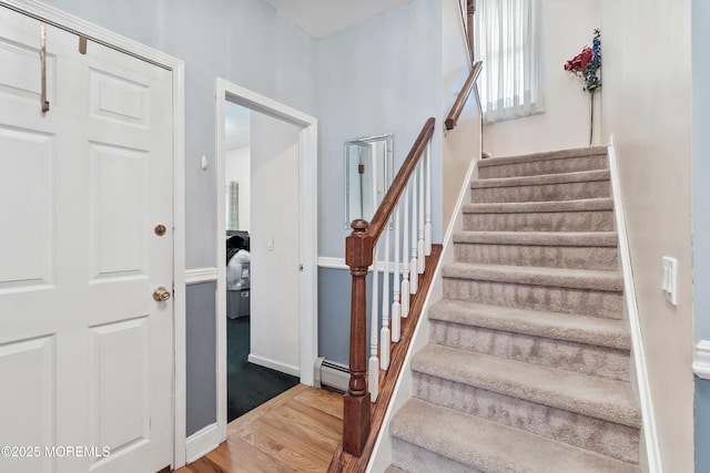 stairway with baseboards, a baseboard heating unit, and wood finished floors