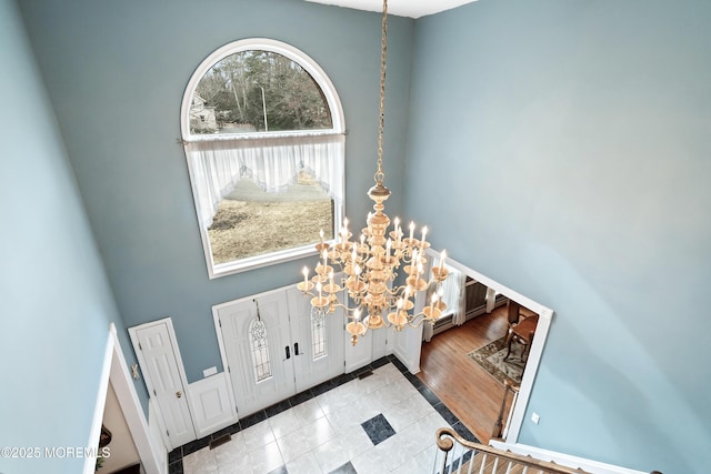 tiled entrance foyer featuring a notable chandelier and a high ceiling