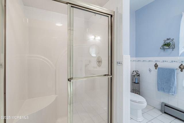 full bath with toilet, tile patterned floors, baseboard heating, a shower stall, and tile walls