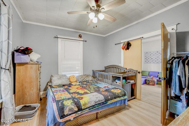 bedroom featuring ornamental molding, wood-type flooring, and ceiling fan