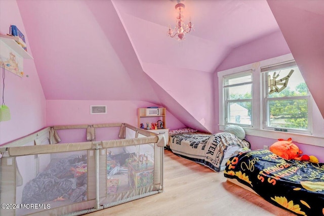 bedroom featuring a notable chandelier, light wood-type flooring, and lofted ceiling