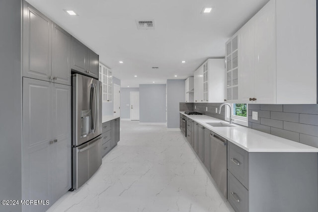 kitchen featuring gray cabinets, backsplash, appliances with stainless steel finishes, and sink