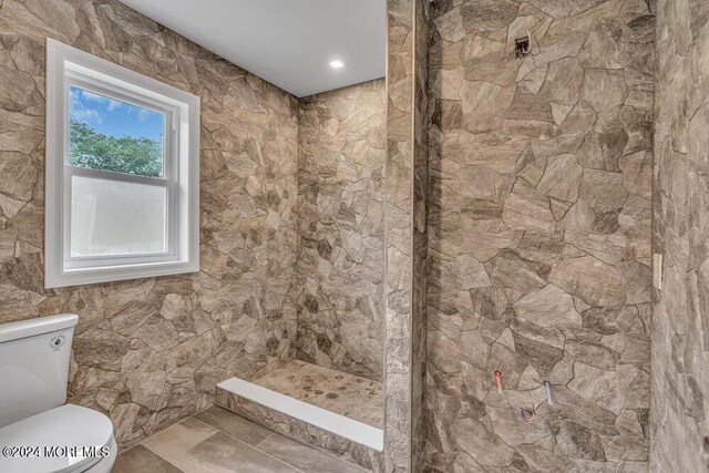 bathroom with a tile shower and toilet