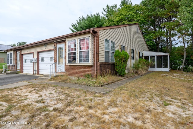 view of front facade with a garage, a sunroom, and a front lawn