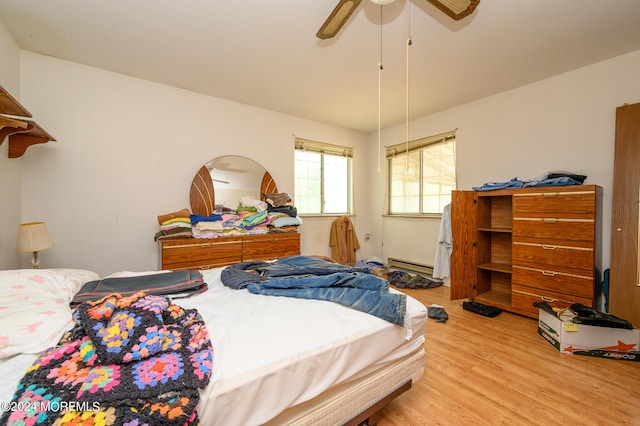 bedroom featuring baseboard heating, light hardwood / wood-style flooring, and ceiling fan