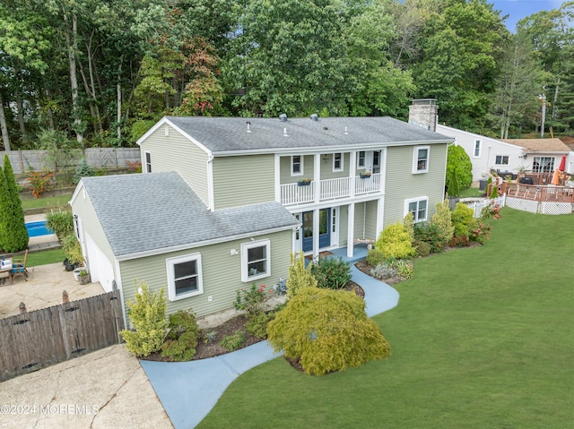 exterior space featuring a shingled roof, a front lawn, fence private yard, a chimney, and a balcony