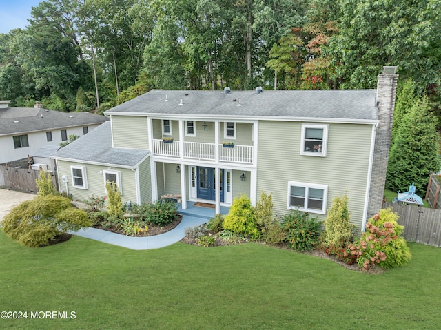 back of property featuring a balcony, a lawn, and fence