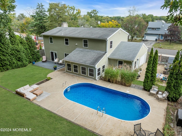 pool with a patio area, a wooden deck, and a yard