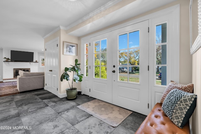 foyer entrance featuring a glass covered fireplace, crown molding, and baseboards