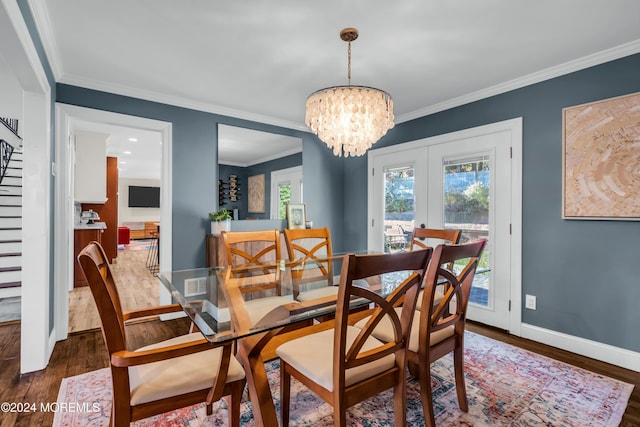 dining space with stairway, wood finished floors, baseboards, an inviting chandelier, and ornamental molding