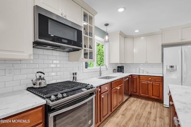 kitchen with white cabinets, appliances with stainless steel finishes, glass insert cabinets, and a sink