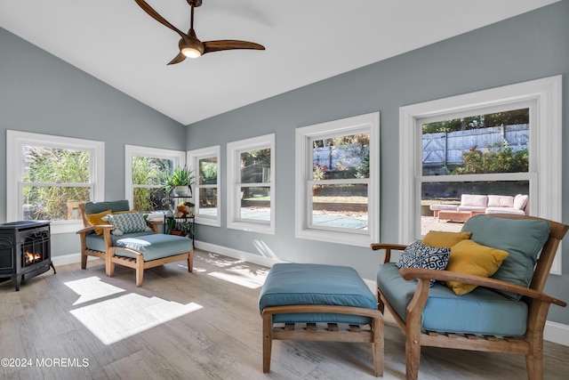 sunroom / solarium with lofted ceiling, ceiling fan, and a wood stove